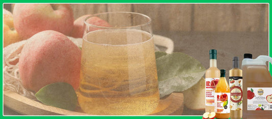 Glass of apple cider vinegar with fresh apples and bottles