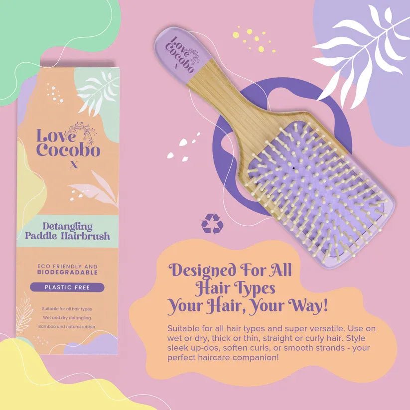 Detangling paddle hairbrush with packaging on a pink background